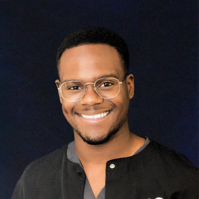 Staff Member Rico Smiling In Front Of Dark Blue Background